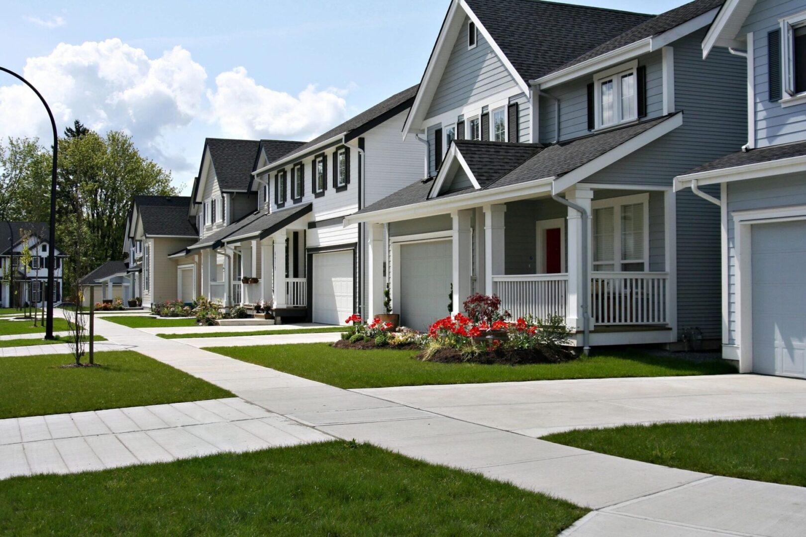 A row of houses with a sidewalk in front.